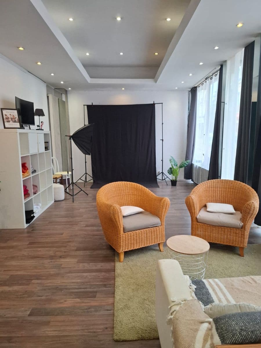 studio photo avec fond noir, fauteuils en osier et mobilier moderne dans un espace lumineux