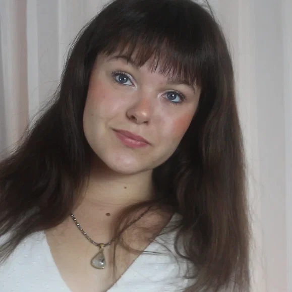 femme souriante avec collier posant devant un fond clair pour Le Comptoir Audiovisuel
